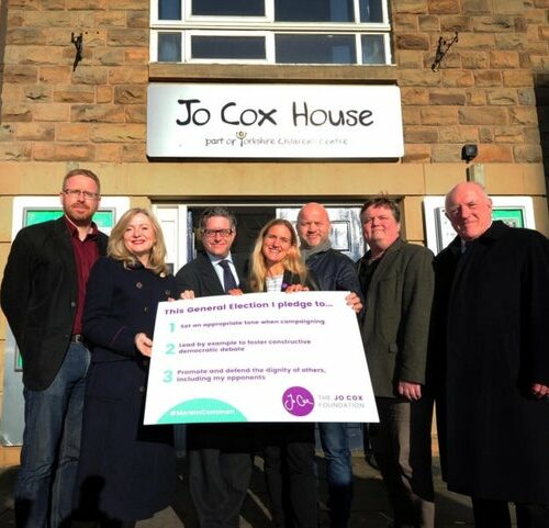 Election candidates holding an 'Election Pledge' banner.